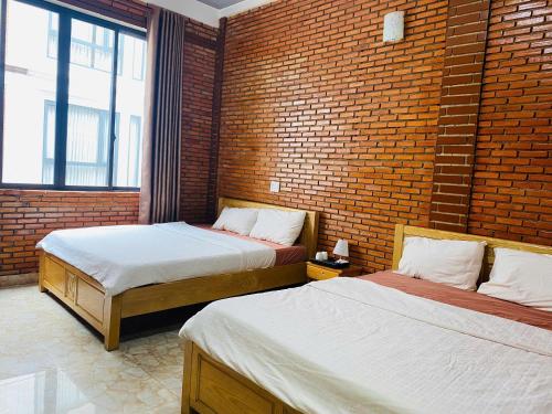 two beds in a room with a brick wall at Dalat Note Hostel in Da Lat