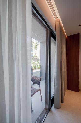 a sliding glass door with a chair in a room at Marbella Sol Hotel - Only Adults in Ksamil