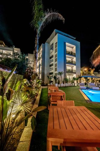 a resort yard with tables and a pool at night at Marbella Sol Hotel - Only Adults in Ksamil