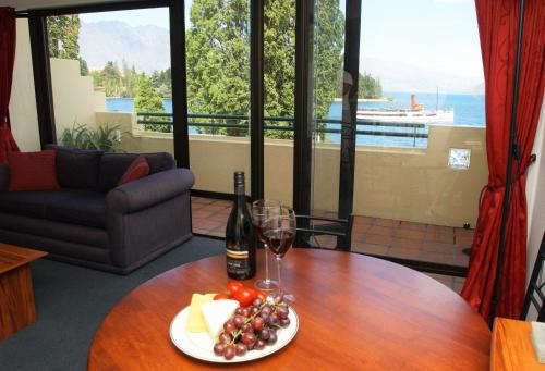 a table with a plate of fruit and a bottle of wine at Lakefront Apartments,18 LAKE ESPLANADE ROAD in Queenstown