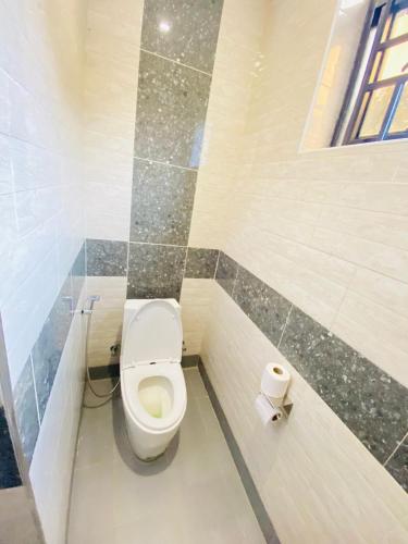 a bathroom with a toilet and a roll of toilet paper at Jikoni Hotel in Gisenyi