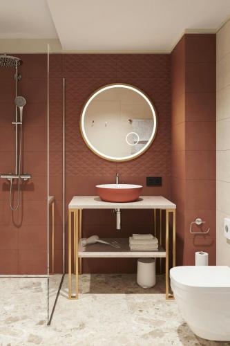 a bathroom with a sink and a mirror at Flesslers Lenggries, a Tribute Portfolio Hotel in Lenggries