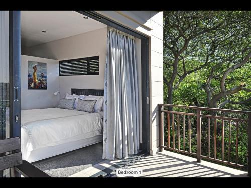 a bedroom with a bed on a balcony at 13 Yellowwood - with back-up power in Ballito