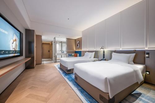 a hotel room with two beds and a flat screen tv at Novotel Hangzhou Yuhang in Yuhang