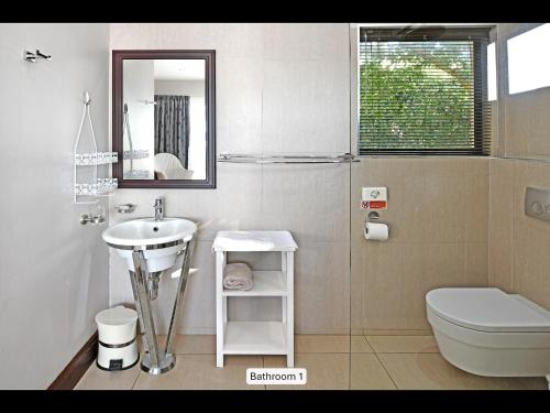 a bathroom with a sink and a toilet and a mirror at 13 Yellowwood - with back-up power in Ballito