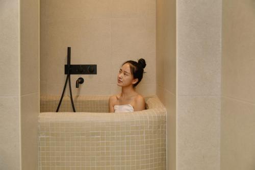 a woman in a tub in a bathroom at Cave Ryokan Hotel by Aank Sungshin Women's University in Seoul