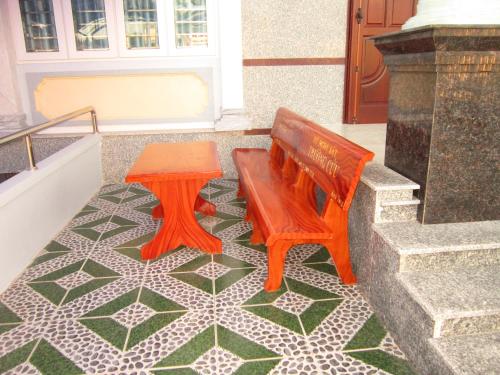 a wooden bench and a stool on a tile floor at Hong Chau Guesthouse in Phu Quoc