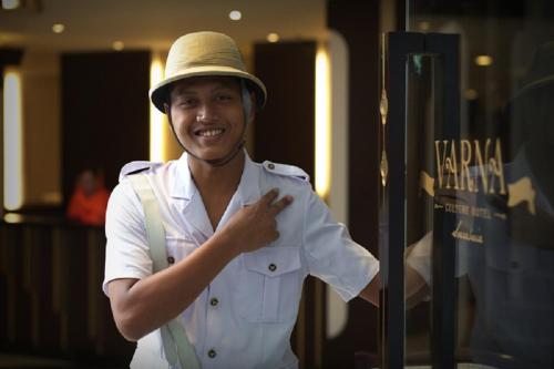 Ein Mann mit einem Hut, der neben einem Fenster steht. in der Unterkunft Varna Culture Hotel Soerabaia in Surabaya