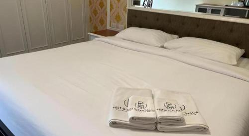 a white bed with two towels on top of it at Rest@Ratchada hotel in Bangkok