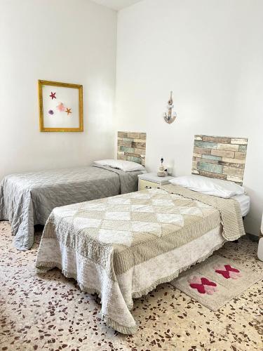 two beds in a room with red shoes on the floor at Casa Nicola - Welchome in San Vito Chietino