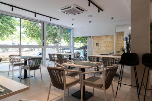 a restaurant with tables and chairs and windows at Hotel Calella by Beatriz Hoteles in Calella