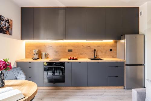 a kitchen with gray cabinets and a stainless steel refrigerator at Symphony City Square Aparthotel in Wrocław