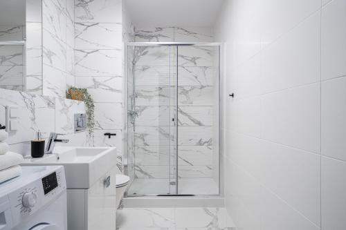 a white bathroom with a shower and a sink at Symphony City Square Aparthotel in Wrocław
