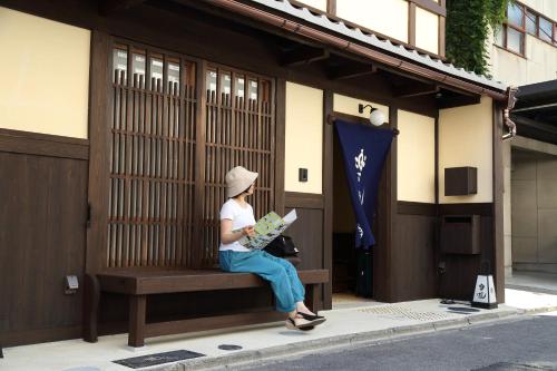 a woman sitting on a bench reading a newspaper at Luck You Kyoto in Kyoto