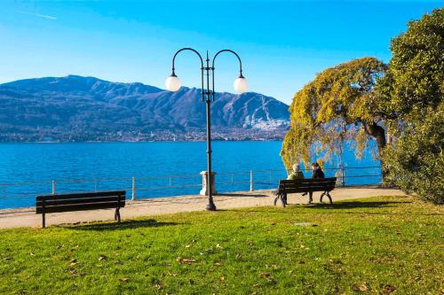twee mensen die op een parkbank naar het water zitten te kijken bij Appartamenti Lungolago in Verbania