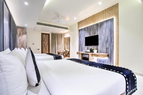 a bedroom with two white beds and a television at Clubhouse Hotel Ayodhya in Ayodhya