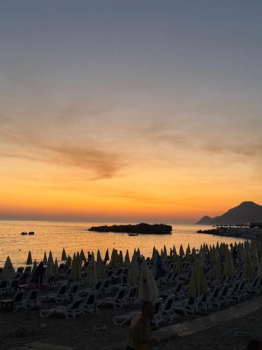 巴尔Nicks sea view apartment I的日落时分带椅子和遮阳伞的海滩