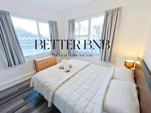 a bedroom with a bed with a white comforter and windows at Affordable Value 3 Cozy Beds 2 Smart Rooms in Lower Hutt