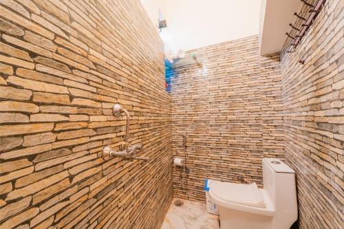 a bathroom with a brick wall and a toilet at Travellers Village-City Center Hertige Home in Jaipur