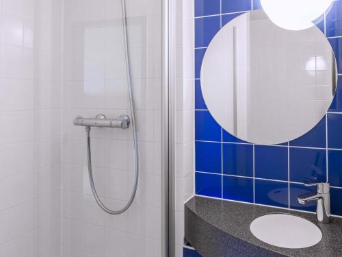 a bathroom with a shower with a mirror and a sink at B&B Hotel Braunschweig-Nord in Braunschweig