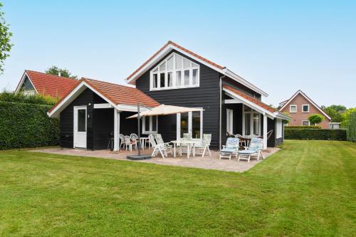 a black house with a patio with chairs and tables at The Black House - Luxurious Holiday Villa Zeewolde in Zeewolde