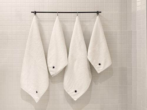 four white towels are hanging on a wall at Hipsters Hotel in Thessaloniki