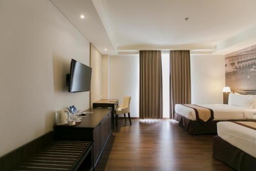 a hotel room with a bed and a television at Varna Culture Hotel Soerabaia in Surabaya