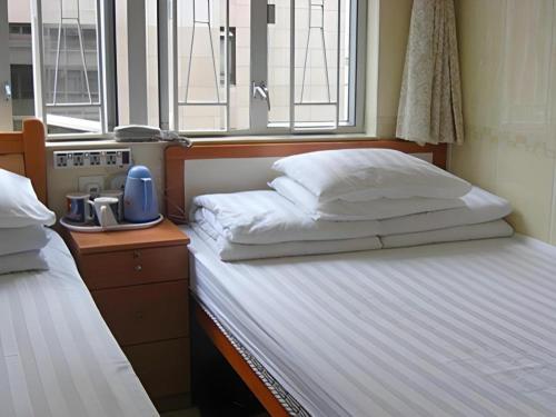 a bedroom with two beds and a window at New Mong Kok Guest House in Hong Kong