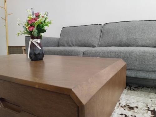 a coffee table in front of a couch with a vase of flowers at Homestay Pinggiran Kota Kuantan in Kuantan