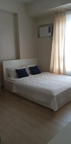 1 dormitorio con cama blanca y almohadas azules en The Verdin Brand-New Unit with Pool, Gym, & High-Speed Wi-fi, en General Trias