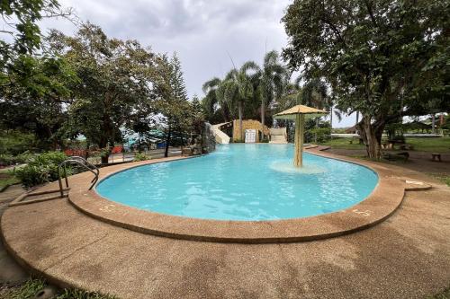a swimming pool with an umbrella in a park at Vista Venice Resort in Morong