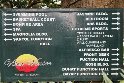 a sign in front of a tree with some food at Vista Venice Resort in Morong