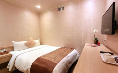 a hotel room with a bed and a television at Red Cabin Inn in Taipei