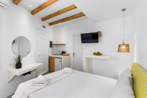 una camera bianca con letto, lavandino e specchio di Ammoudi a Paroikia