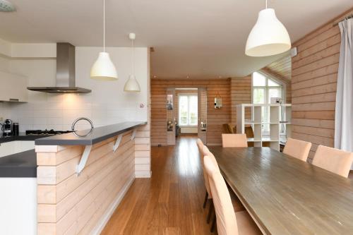 a kitchen and dining room with a wooden table at The Black House - Luxurious Holiday Villa Zeewolde in Zeewolde