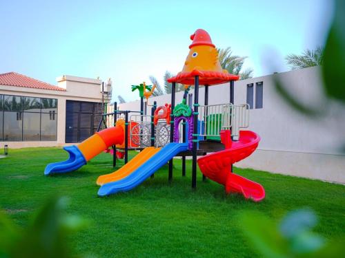 a playground with a slide in the grass at Calm Zone Luxury Private Pool 5BHK Villa in Al Ḩalāh
