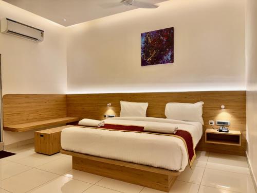 a bedroom with a large bed and a painting on the wall at Triviera Hotel Chirala in Chīrāla