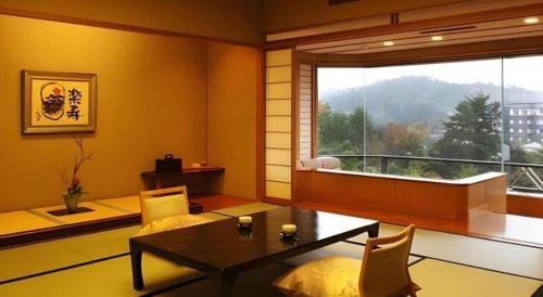 a living room with a table and a large window at Shiratamano Yu Kahou in Shibata