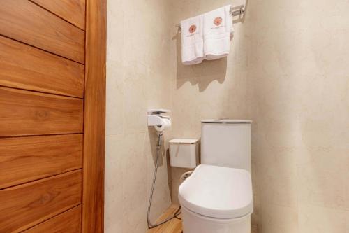 a bathroom with a toilet and towels on the wall at Uma Nandhi Villa Ubud in Tegalalang