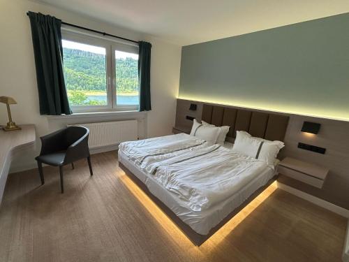 a bedroom with a bed and a chair and a window at Berghof am See in Langelsheim