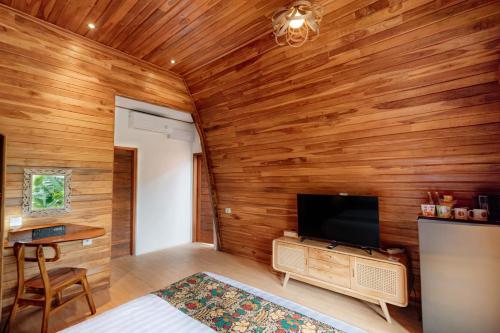 a room with a wooden wall with a flat screen tv at Uma Nandhi Villa Ubud in Tegalalang