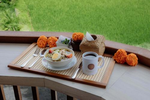 a tray with a bowl of food and a cup of coffee at Uma Nandhi Villa Ubud in Tegalalang