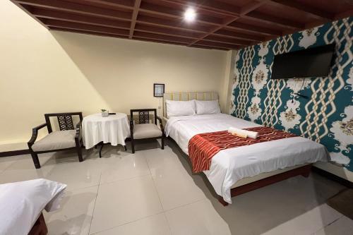 a bedroom with a bed and a table and a tv at Vista Venice Resort in Morong
