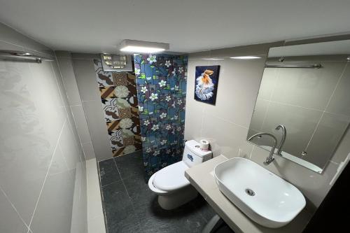 a bathroom with a white toilet and a sink at Vista Venice Resort in Morong