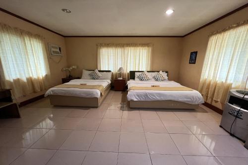a bedroom with two beds and windows with curtains at Vista Venice Resort in Morong