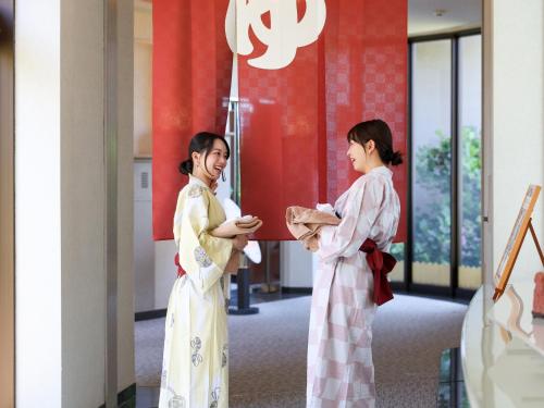 two women in kimonos standing in a hallway at Ikoi no mura Notohanto in Shika