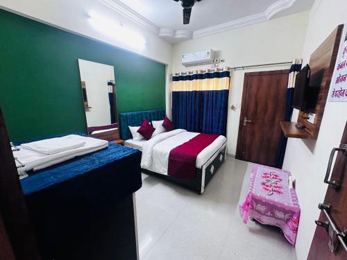 a bedroom with two beds and a green wall at Vashistha Homestay in Ujjain