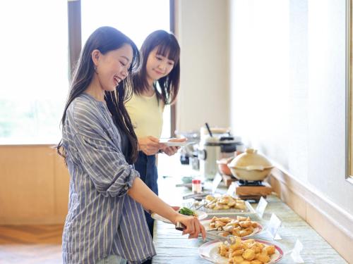 two women standing in a kitchen preparing food at Ikoi no mura Notohanto in Shika