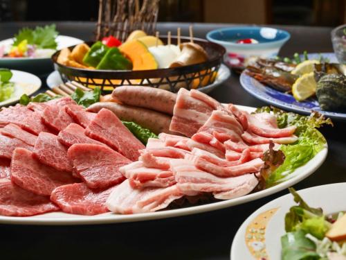 a plate of meats and vegetables on a table at Ikoi no mura Notohanto in Shika