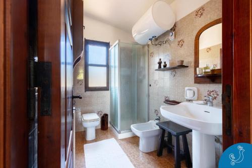 a bathroom with a sink and a toilet and a shower at Villa Anna - Charming dimora suspended over the sea in Geremèas